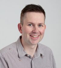 A head and shoulders image of a man in a grey shirt